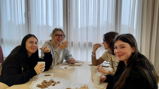 Vier Schülerinnen sitzen zusammen und verkosten Tee und Kekse